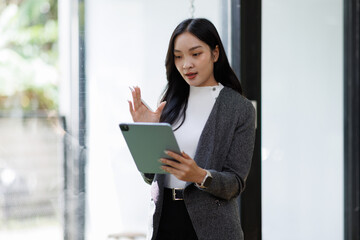 professional business asian woman looking at camera and smiling. businesswoman CEO holding digital tablet phone using fintech tab application standing at workplace in office.
