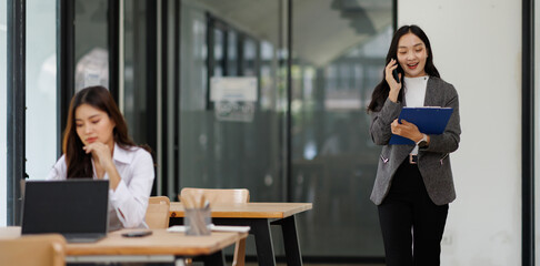 professional business asian woman looking at camera and smiling. businesswoman CEO holding digital tablet phone using fintech tab application standing at workplace in office.
