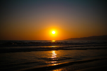 Obraz premium Bright orange sunset over sea with glowing light on water