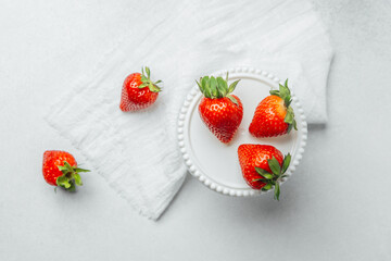 Bright fresh strawberries on a white plate with a linen cloth