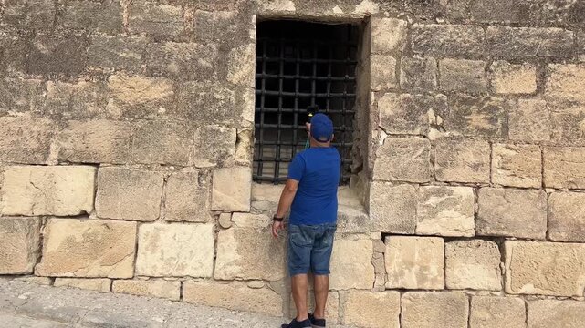 Turista filmando a trav&eacute;s de una ventana una mazmorra en el Castillo de Santa B&aacute;rbara, Alicante, 4K