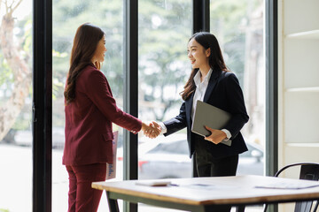 Two excited happy Young Asian businesswomen discuss with new startup project Idea presentation, analyze planning and financial statistics and investment market at office.
