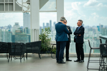 Businessmen networking on rooftop terrace, discussing ideas and strategies, reflecting leadership,...