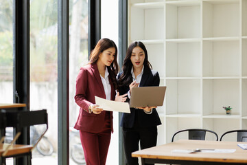 Two business asian women sitting and using the technology laptop in the modern workplace, Business lifestyle and technology concept
