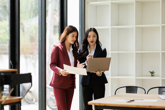 Two business asian women sitting and using the technology laptop in the modern workplace, Business lifestyle and technology concept
