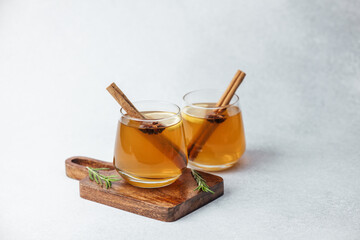 Warm apple cider with cinnamon sticks, star anise, and rosemary on wooden board, bright © reddish