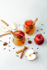 Warm apple cider with cinnamon sticks, star anise, and cloves on light background
