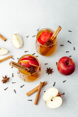 Apple slices and cinnamon sticks in glasses, spiced drinks with star anise and cloves