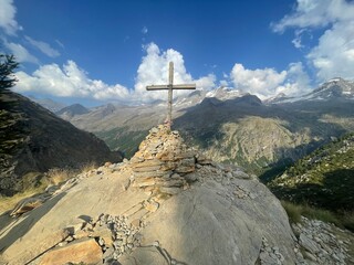 Summit view featuring the Croce di Arolley, a wooden cross mounted on a pile of rocks at high altitude in Valsavarenche, within the Gran Paradiso National Park, Aosta Valley, Italy