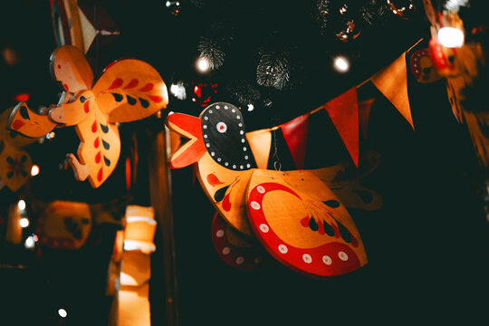 Handmade wooden bird ornaments with colorful paint hang at night with festive flags