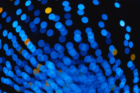 Abstract background blue and yellow bokeh circles on dark backdrop, festive glowing lights