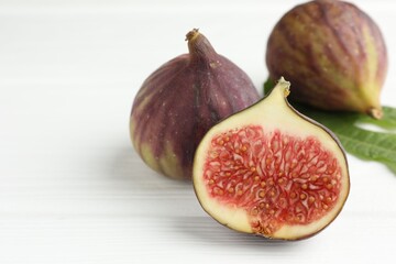 Whole and cut figs on white wooden table, closeup. Space for text