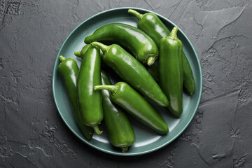 Fresh jalapeno peppers on black textured table, top view