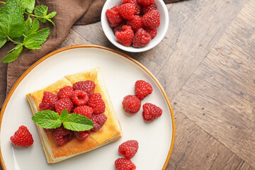 Yummy puff pastry with raspberries and mint on wooden table, flat lay. Space for text
