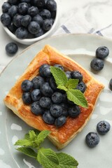 Tasty puff pastry with blueberries and mint on white marble table, flat lay