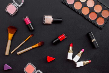 Flatlay of makeup cosmetics on black table. Blusher, mascara and lipstick, top view