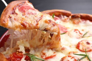Taking piece of delicious pizza with cheese and tomatoes on dark background, closeup