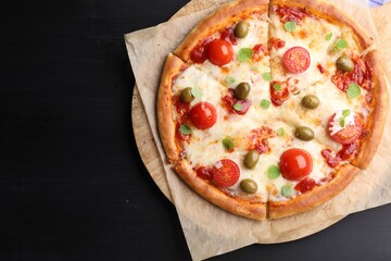 Delicious pizza with cheese, tomatoes and olives on black wooden table, top view. Space for text