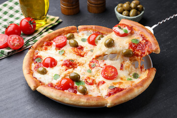 Taking piece of delicious pizza with cheese, tomatoes and olives at dark grey table, closeup