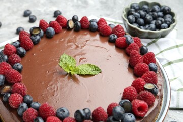 Delicious chocolate cheesecake with berries and mint on table, closeup