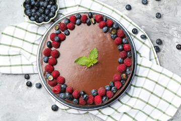 Delicious chocolate cheesecake with berries and mint on grey table, flat lay