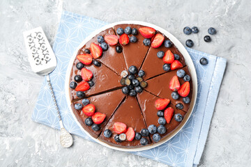 Tasty chocolate cheesecake with berries and server on light grey textured table, flat lay