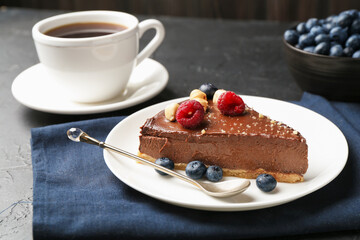 Piece of delicious chocolate cheesecake with nuts, berries and tea on black table, closeup