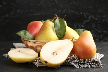 Many fresh pears and leaves in wicker bowl on black table, closeup