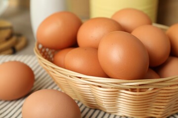 Raw chicken eggs in wicker basket on table, closeup
