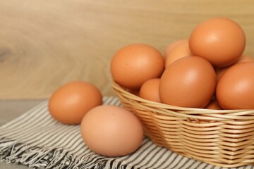 Raw chicken eggs in wicker basket on countertop, closeup