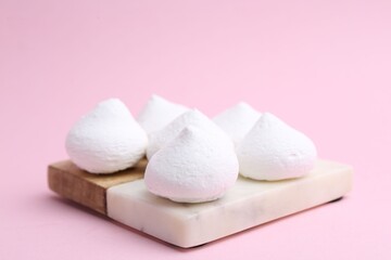 Many yummy meringue cookies on pink background, closeup
