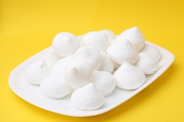 Yummy meringue cookies on yellow background, closeup