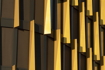 An abstract closeup of the contemporary buildings golden facade highlights its angular elements, showcasing the dynamic nature of architectural design in the urban landscape