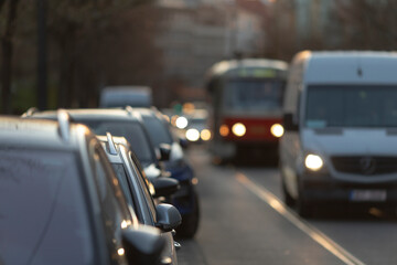 The bustling urban street showcases a variety of parked cars and busy buses, with commercial vehicles skillfully navigating the vibrant scene full of activity and energetic movement