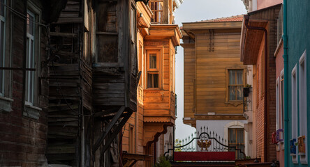 The contrasting textures and colors of weathered wooden homes and vibrant, newly restored buildings line a narrow alley, showcasing the architectural diversity in a historic European neighborhood.