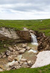 the sources of a mountain river high in the mountains on alpine meadows during the melting of snow, morning in nature
