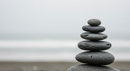Serene stacked stones create perfect balance on tranquil beach with ocean backdrop
