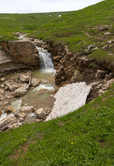 the sources of a mountain river high in the mountains on alpine meadows during the melting of snow, morning in nature