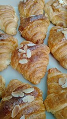 Golden brown almond croissant pastry, drizzled with sweet honey glaze, offers delightful bakery treat. Freshly baked and warm, it provides comforting breakfast or snack, evoking pure joy