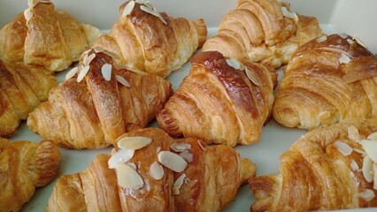 Golden, flaky croissant pastries, each featuring delightful almond topping and sweet honey glaze, beckon warmly. Fresh baked treats offer an inviting, delicious taste sensation for morning