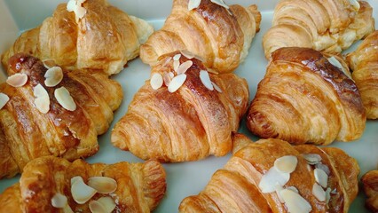 Golden croissants, freshly baked and glistening with sweet honey glaze, offer delightful morning treat. Each flaky pastry is generously topped with crunchy almond slices, promising truly