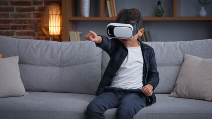 African American child boy kid son playing VR game at home play online 3d gaming with virtual reality glasses augmented headset AR technology gaming playing metaverse pretending fighting innovation