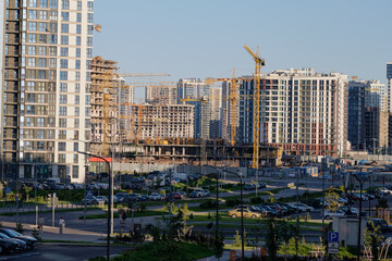 Fototapeta premium Construction sites are busy with cranes and workers as new high-rise buildings take shape in a growing urban area during mid-afternoon
