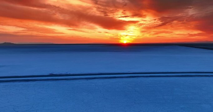 Contrasting blue of the salt pan in Tooele County in northwestern Utah, United States and orange sky. Fantastic sunset at the Bonneville Salt Flats from drone.