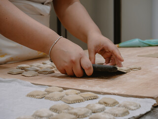 Young woman's hands expertly craft traditional Italian stuffed pasta tortelli in a professional kitchen setting showcasing culinary skill and dedication to authentic food preparation