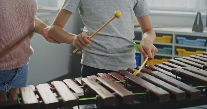 Close Up of Primary School Boy Practicing Xylophone in Modern Music Class, Dreaming to Become Musician. Teacher Guiding Talented Student to Play Percussion Instrument. Rhythm Education, Music Training