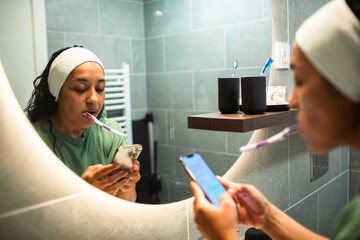 Woman brushing teeth and using phone