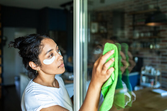 Woman cleaning window with eye patches
