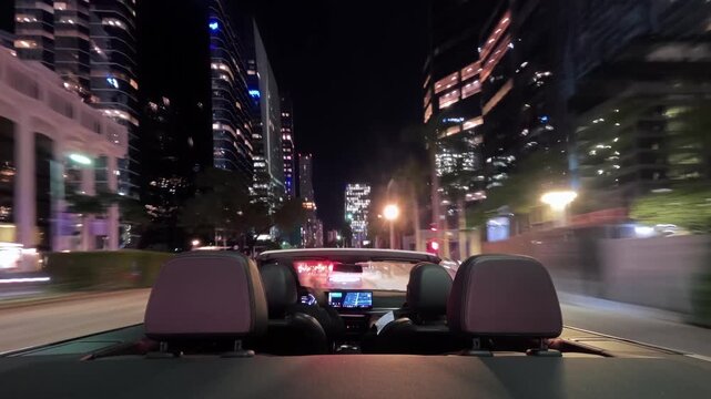 Group of friends driving a convertible car at night in Miami, Florida. Cinematic hyper-lapse motion with illuminated skyscrapers, city lights, and nightlife atmosphere