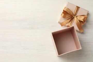 Open gift box with beautiful lid on white wooden table, top view. Space for text